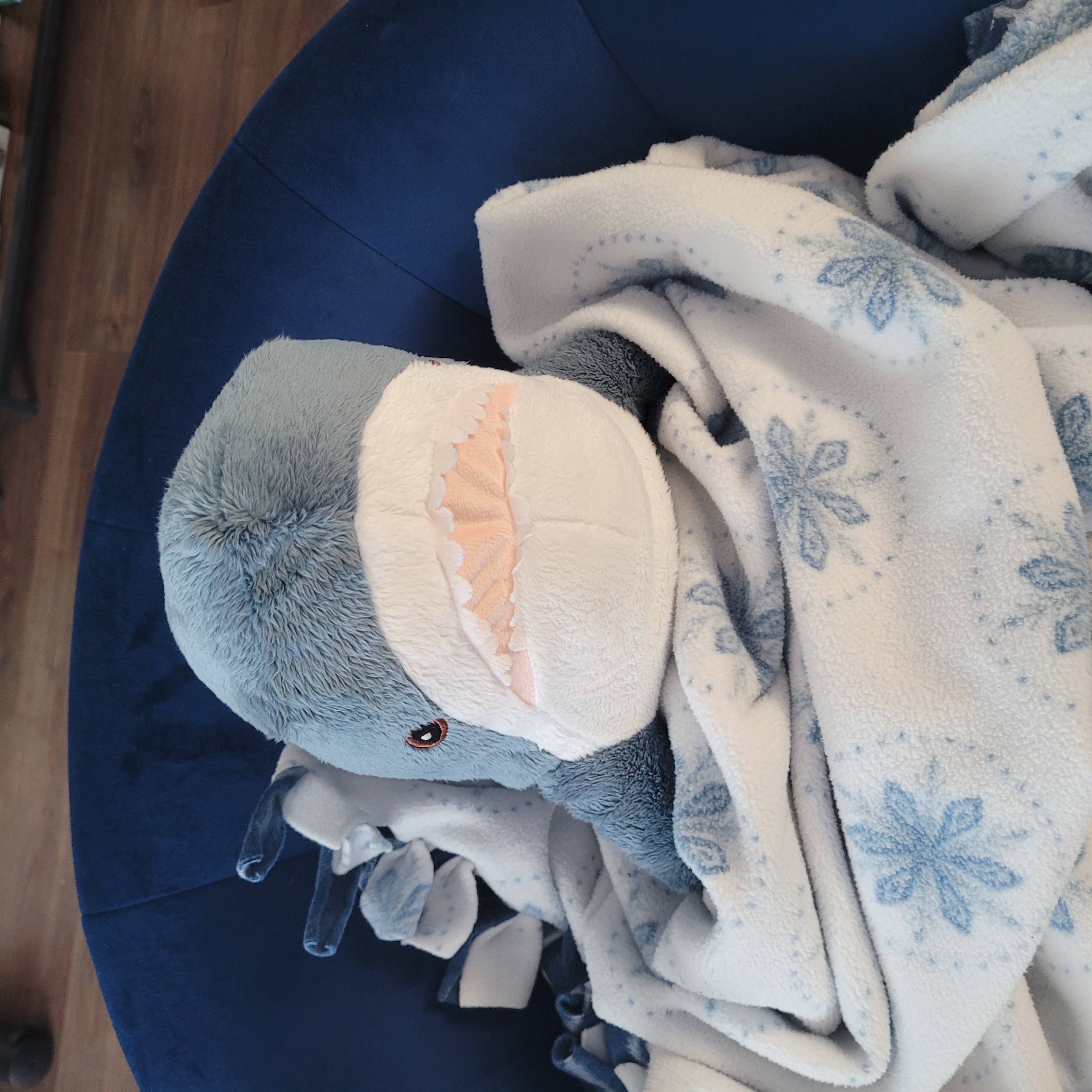 blue shark plushie, called blåhaj, in a snowflake patterned blanket